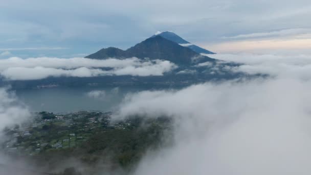 Slow aerial dolly shot flying through the clouds past small valleys towards lake Batur and mount Agung in Bali, Indonesia — Stock video