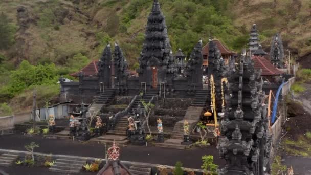 Ascending pedestal aerial view of stunning black stone pillars and colorful statues at the Pura Pasar Agung Hindu Temple on the side of Mount Agung in Bali — Stockvideo