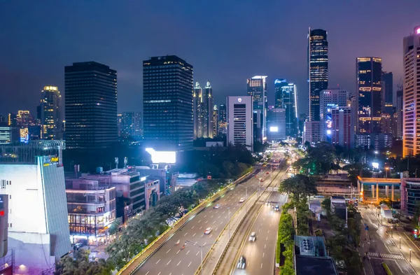 Cakarta 'da gökdelenleri olan şehir merkezindeki hızlı gece trafiğinin görüntüsü, Endonezya Havayolları şehir boyunca uzanan çok şeritli otoban manzarası.