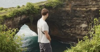 Erkek turistin Bali Endonezya 'daki Kırık Plaj Pasih Uug' un güzel uçurumlarına bakarken yakın çekimleri.