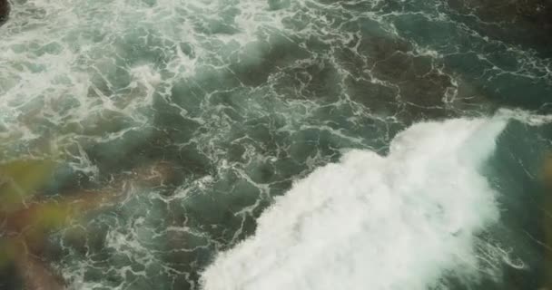 Zárja be a lassított felvétel a hullám mozog a vízen, és összeomlik a parton a sziklás trópusi strand Fehér örvénylő tengeri hab által alkotott hullámok — Stock videók