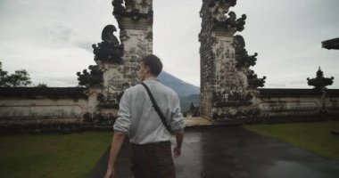 Bali 'deki Pura Penataran Agung Lempuyang tapınağında Cennetin Kapıları' na doğru yürüyen bir adamın orta ölçekli fotoğrafı Agung Dağı yanardağı ve tapınak zeminini gözler önüne seriyor.