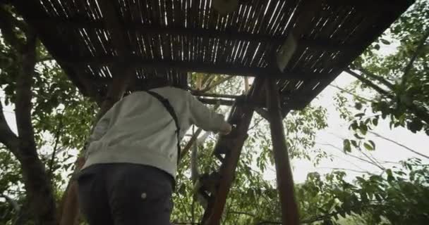 Close up cirkelend uitzicht op een man klimmend in een houten wildlife observatie hut in tropisch klimaat in Azië — Stockvideo