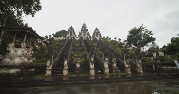 Camión de ángulo bajo disparado del famoso templo Pura Penataran Agung Lempuyang en Bali después de la lluvia Antiguas esculturas de piedra y escaleras en el templo hindú en la ladera del Monte Lempuyang — Vídeos de Stock