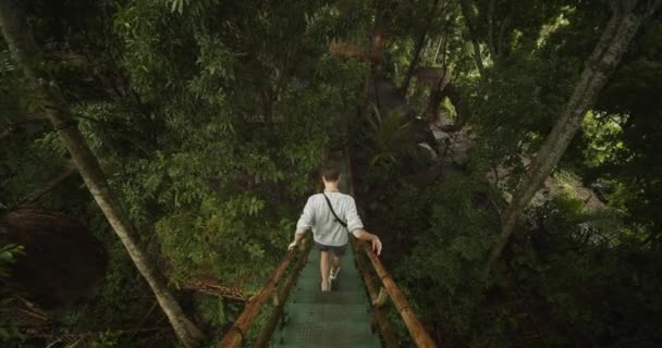 Dolly atirou seguindo um homem descendo as escadas da cabana de observação de madeira em uma floresta tropical Turista masculino explorando a selva na chuva — Vídeo de Stock