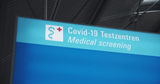 Vista de cerca de la señal hacia las instalaciones de pruebas COVID. Prevención de la propagación del coronavirus y pruebas obligatorias a la llegada. — Vídeos de Stock