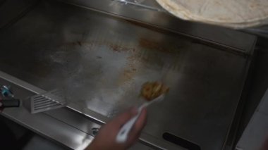 Şef çeşitli sebzeleri metal endüstriyel mutfak ocağına koyuyor. Aşçı, kızgın metal mutfak sobasına taze sebze ekliyor.