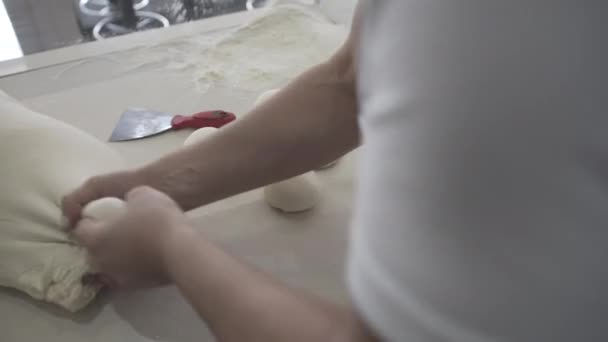 Boulanger professionnel faisant des boules de pâte à partir d'un grand morceau de pâte crue. Baker préparant la pâte pour le pain et la pâtisserie — Video