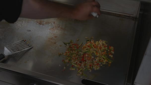 在热盘子里的蔬菜混合物中加入盐，然后用勺子将煮沸的蔬菜分离出来。厨师在餐馆厨房的金属炉子上烹调蔬菜 — 图库视频影像