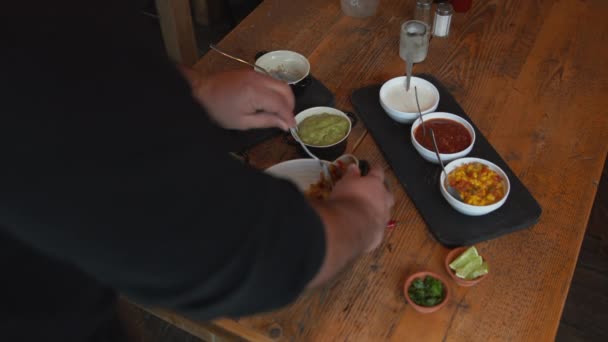 Kook het toevoegen van verschillende sauzen en salsa in traditionele Mexicaanse schotel in een kom. Het toevoegen van een verscheidenheid aan ingrediënten uit de schalen in de uiteindelijke schotel — Stockvideo
