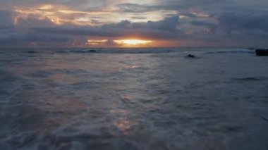 Bali 'de altın gün batımında alçak hava dalgaları. Okyanus dalgalarının güzel, sıcak bir akşam ışığında kıyıya vurması.