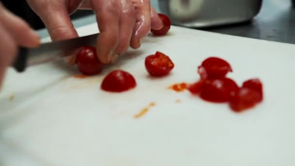 Mes snijden kleine rode tomaten in kleine blokjes. Close-up weergave van het snijden van meerdere kerstomaten in kleinere stukken — Stockvideo
