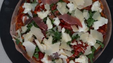 Domatesli İtalyan pizzası, peynir, prosciutto ve roka manzarası. Gurme malzemeli pizzanın en alt görünümü
