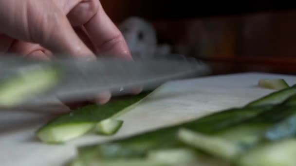 Yeşil salatalıkları ince dilimlere ayırmanın yakın görüntüsü. Mutfakta yeşil sebze hazırlığı var. — Stok video