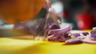 Kırmızı soğanı ince dilimlere ayıran bıçağın yakın görüntüsü. Mor bir sebzeyi çabucak doğrayan bir aşçının yakın görüntüsü.