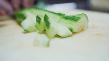 Küçük küplere salatalık doğrayan ve domates salatasına ekleyen bıçak görüntüsünü kapat.