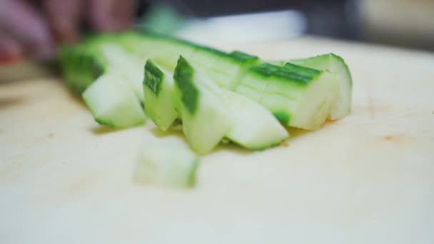 Close-up zicht op mes snijden komkommer in kleine blokjes en ze toe te voegen aan de tomatensalade — Stockvideo