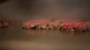 Lokanta mutfağındaki ocakta köfte çeviren bir aşçıya yaklaş. Fast food işçisi fast food restoranında spatulayla hamburger çeviriyor.