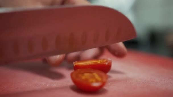 Küçük vişneli domatesleri ikiye bölmek. Küçük domatesleri bıçakla ikiye bölme görüntüsünü kapat. — Stok video