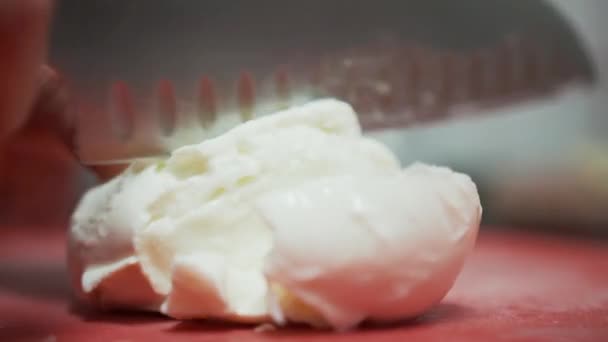 Cutting mozzarella ball on thin slices. Close up view of slicing large mozzarella ball into thin slices with a knife — Stock Video