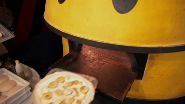 Sıcak bir fırına taze meyve pizzası koyma manzarası. Meyveli pizzayı uzun bir spatulayla büyük bir fırının içine koymak. — Stok video