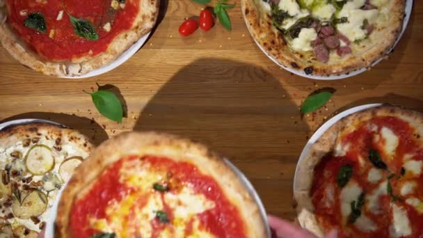 Sirve pizza italiana tradicional con albahaca, queso y salsa de tomate en la mesa de madera. Vista de arriba hacia abajo de varias pizzas deliciosas sobre la mesa — Vídeo de stock