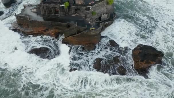 Veduta aerea di rocce pericolose e forti onde che si schiantano contro la scogliera off shore con il tempio Tanah Lot a Bali, Indonesia — Video Stock