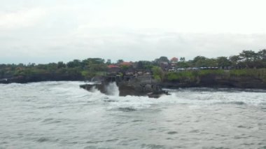 Endonezya 'nın Bali kentindeki Tanah Lot Tapınağı' na yaklaşan alçak hava görüntüsü. Tehlikeli dalgalar ve dalgalar Bali kıyı şeridinde küçük bir adaya çarpıyor.
