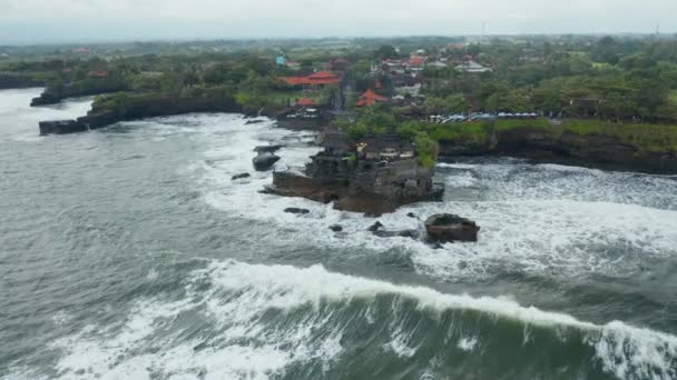 Széles panoráma nyílik Tanah Lot templom veszélyes tengerben. Erős óceáni hullámok zuhannak sziklák körül híres turisztikai célpont Bali, Indonézia — Stock videók