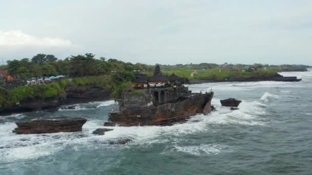 Güçlü okyanus dalgaları Endonezya, Bali 'deki Tanah Lot tapınağıyla kayalık kayalıklara çarpıyor. Denizdeki ünlü turizm merkezini çevreleyen hava görüntüleri — Stok video