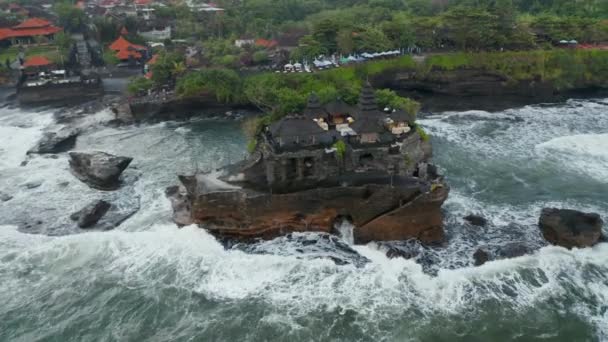 Nad głową antena obraca się widok na wspaniałe budynki w świątyni Tanah Lot na ciemnym klifie oceanu w wzburzonym morzu na Bali, Indonezja — Wideo stockowe