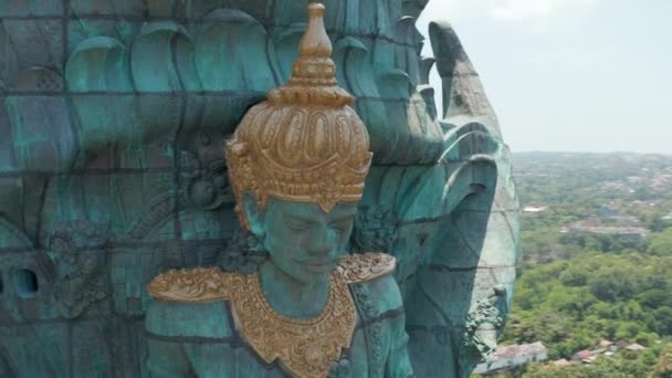 Gezicht van de Hindoe godheid Vishnu in Garuda Wisnu Kencana standbeeld in Bali, Indonesië. Close-up luchtfoto van religieuze figuur op grote koperen standbeeld dat boven de stad — Stockvideo