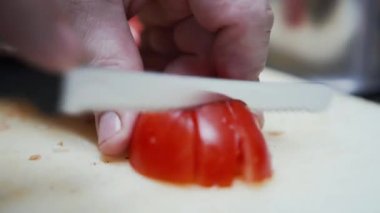 Domatesleri küçük küplere ayıran bıçağın yakın görüntüsü. Kırmızı domatesleri küçük parçalara ayırmak