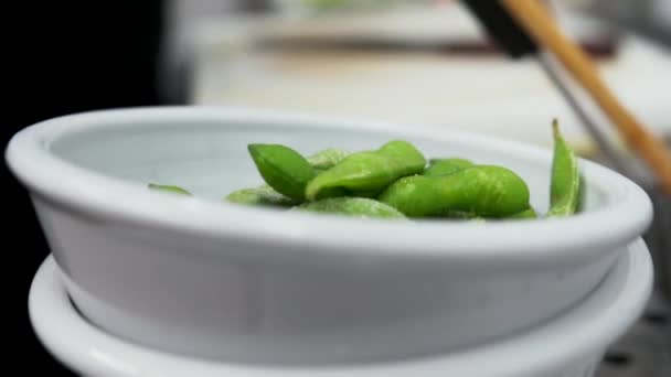 Προσθέτουμε ένα μπολ με πράσινα φασόλια σε μια κατσαρόλα με βραστό νερό. Προσθέτοντας πράσινα φασόλια στο πιάτο σε μια κουζίνα εστιατόριο — Αρχείο Βίντεο