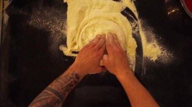 Profesyonel bir aşçının pizza hamurunu düz pizza ekmeğine sarması. Şefin mısır unundan pizza yaptığı en tepeden aşağı manzara.