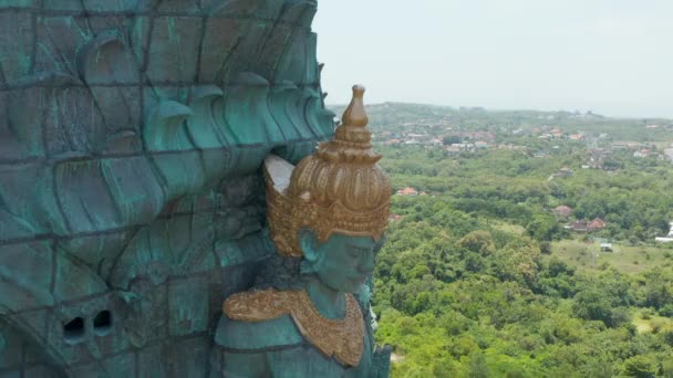 Статуя Гаруда Вісну Кенкана на Балі, Індонезія. Закройте повітряний вид на обличчя індуського бога Вішну, який їде на Гаруді. Гігантська мідна синя і зелена релігійна статуя — стокове відео