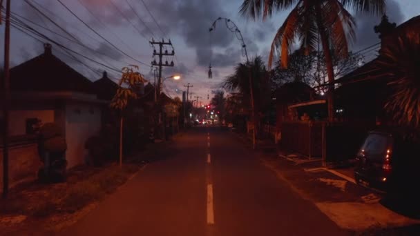 在印度尼西亚巴厘岛，摩托车在一条黑暗的街道上行驶。亚洲日落后的城市街道交通 — 图库视频影像