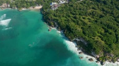 Bali kıyı şeridinde dalgaların kayalık kayalıklara çarpması. Bereketli tropikal kıyılarda turkuaz mavi deniz kıyısında lüks tatil beldeleri