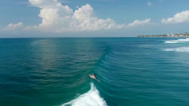 Vista aérea de pessoas surfando através das ondas no oceano azul tropical. Onda rápida rompendo a superfície do oceano — Vídeo de Stock