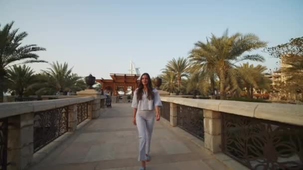 妇女走过迪拜的大桥，背后是Burj Al Arab 。迪拜街头漫步的迷人女子的前景 — 图库视频影像