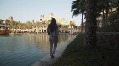 Dubai 'de lüks bir mahallede su kenarında yürüyen bir kadın. Birleşik Arap Emirlikleri 'nin kentsel mahallesinde lüks yaşam tarzı
