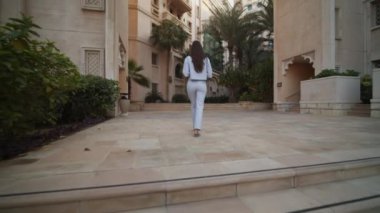 Dubai 'deki zengin yerleşim bölgesinde yürüyen bir kadını takip etmek. Birleşik Arap Emirlikleri 'nde lüks evlerle çevrili kadın turist manzarası