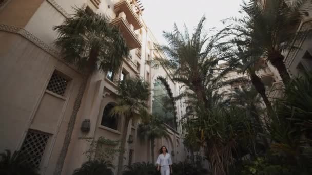 Mujer caminando en un barrio residencial de lujo en Dubai. Atractiva mujer caminando por la calle con apartamentos de lujo en Emiratos Árabes Unidos — Vídeos de Stock