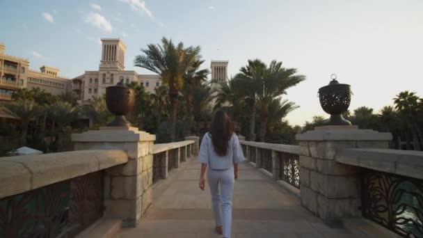 Žena kráčí přes most směrem k luxusní rezidenční čtvrti v Dubaji. Po atraktivní žena procházky v luxusních čtvrtích ve Spojených arabských emirátech