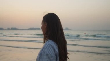 Dubai 'de kumlu sahilde yürüyen zarif elbiseli esmer kadının yakın görüntüsü.