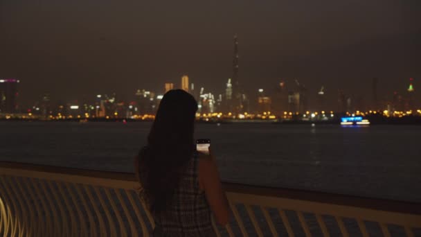 Femme prenant des photos des gratte-ciel de Dubaï la nuit. Touriste prenant des photos du paysage urbain de Dubaï avec son téléphone — Video