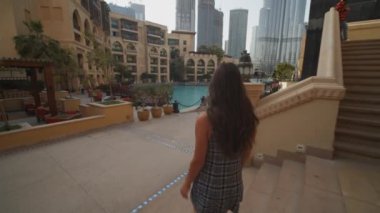 Dubai 'nin şehir merkezinde Burj Khalifa gökdeleniyle yürüyen bir kadını takip ediyorum. Dubai 'de havuzu olan lüks bir otelde turist geziyor.