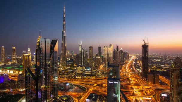 Día a noche timelapse del centro de la ciudad de Dubai con rascacielos altos modernos y tráfico callejero ocupado en una carretera. Time lapse de Dubai con luces brillantes de la ciudad por la noche — Vídeos de Stock