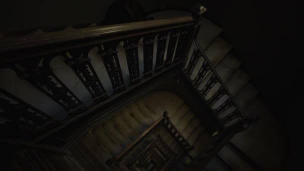 Tilt into overhead view of old wooden staircase leading in the darkness. Old brown rustic stairwell descending into darkness — Stock Video