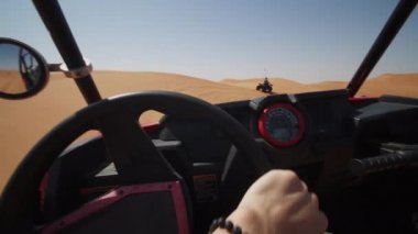 Çölde kum tepecikleri üzerinde kum arabası sürme bakış açısı. Çöldeki off-road aracının direksiyonunun yakın görüntüsü